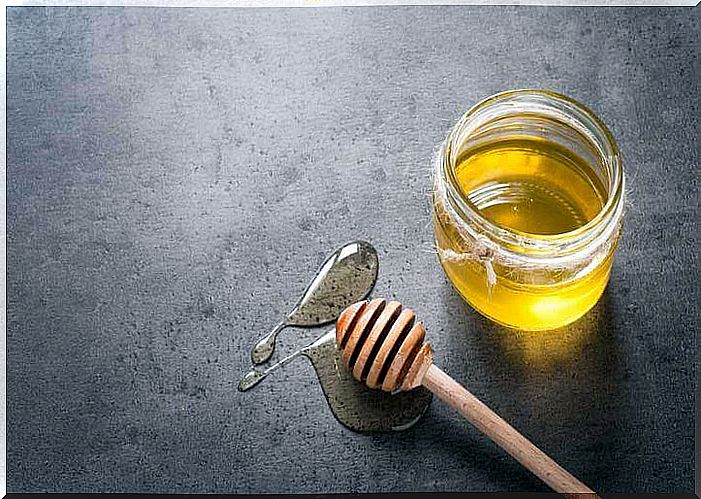 A jar of honey with a wooden spoon