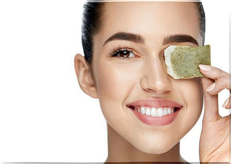 Woman holds a tea bag to her eye