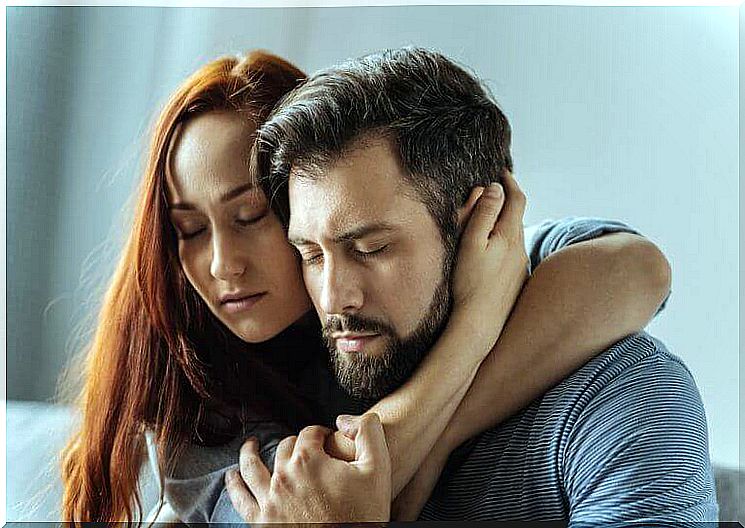 A woman hugs a man and offers him support.