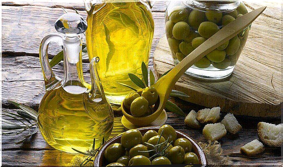 Olives in a bowl and olive oil in two bottles.